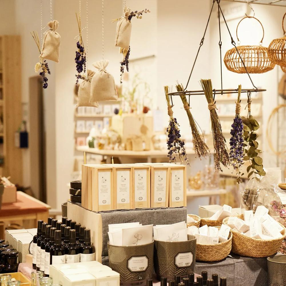 Ein Laden mit Körben, getrocknetem Lavendel, Flaschen und Seifen auf einem Tisch, umgeben von hängenden Dekorationen.