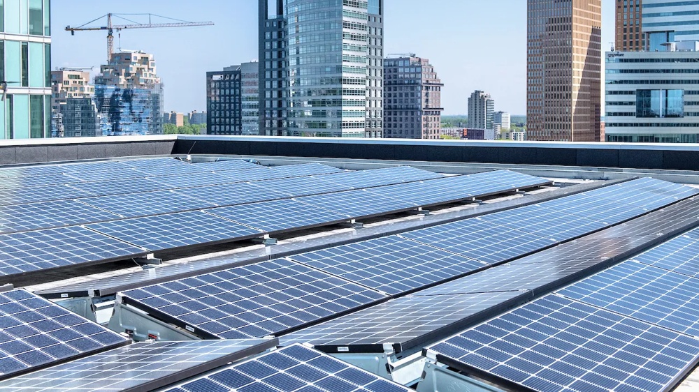 Solarmodule auf einem Dach mit modernen Hochhäusern im Hintergrund.