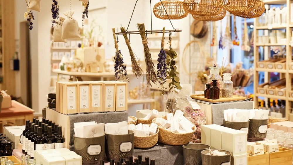 Ein Laden mit Körben, getrocknetem Lavendel, Flaschen und Seifen auf einem Tisch, umgeben von hängenden Dekorationen.