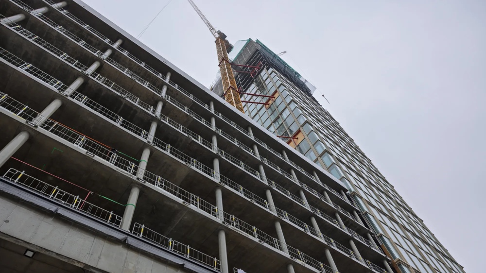 Rohbau eines mehrstöckigen Gebäudes mit Gerüsten und Baukran im Hintergrund.