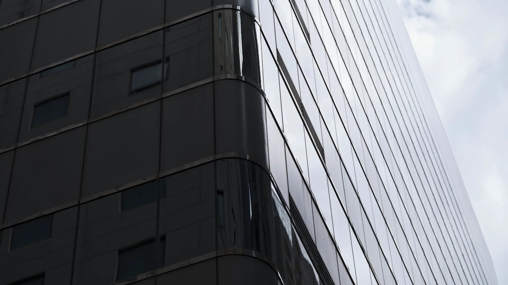 Ein modernes Hochhaus mit verspiegelter Glasfassade unter bewölktem Himmel.