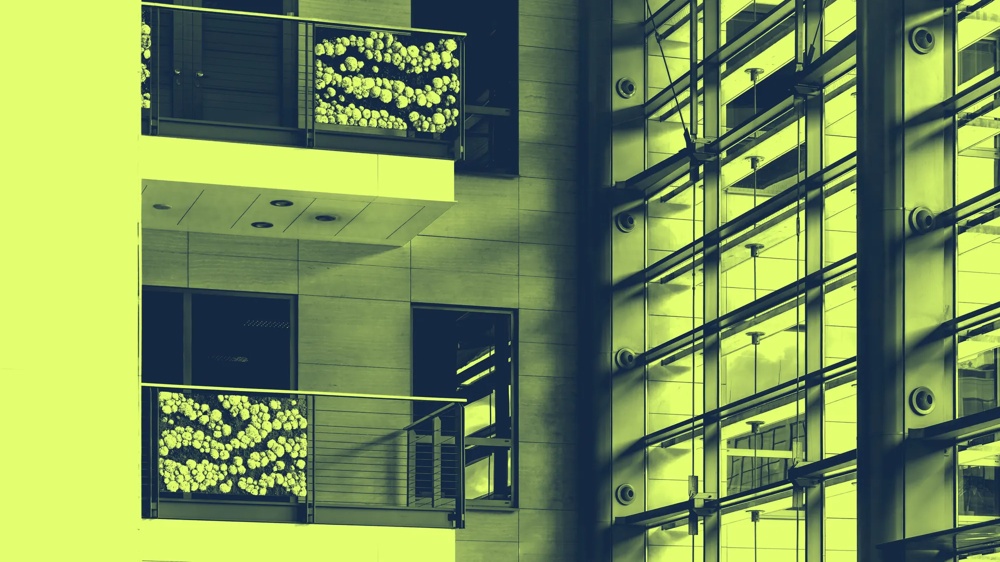 Balkon mit Blumendekoration an modernem Gebäude, neben Glasfassade mit Schattenlinien.