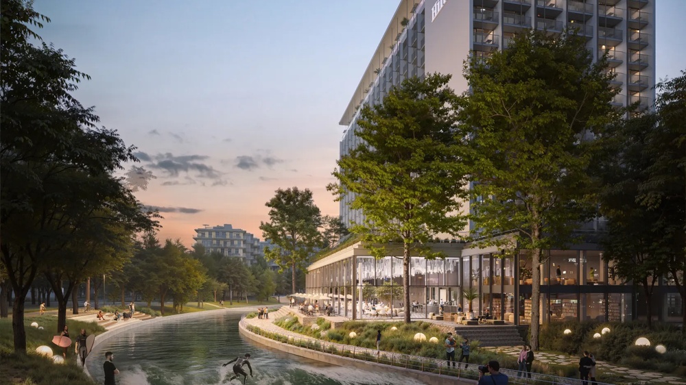 Ein modernes Hotel am Fluss bei Sonnenuntergang, umgeben von Bäumen und Spaziergängern.