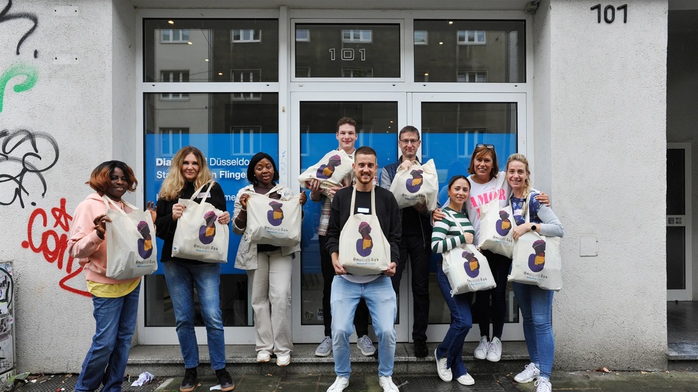 Gruppe von Menschen hält Taschen vor einem Gebäude mit blauer Tür.