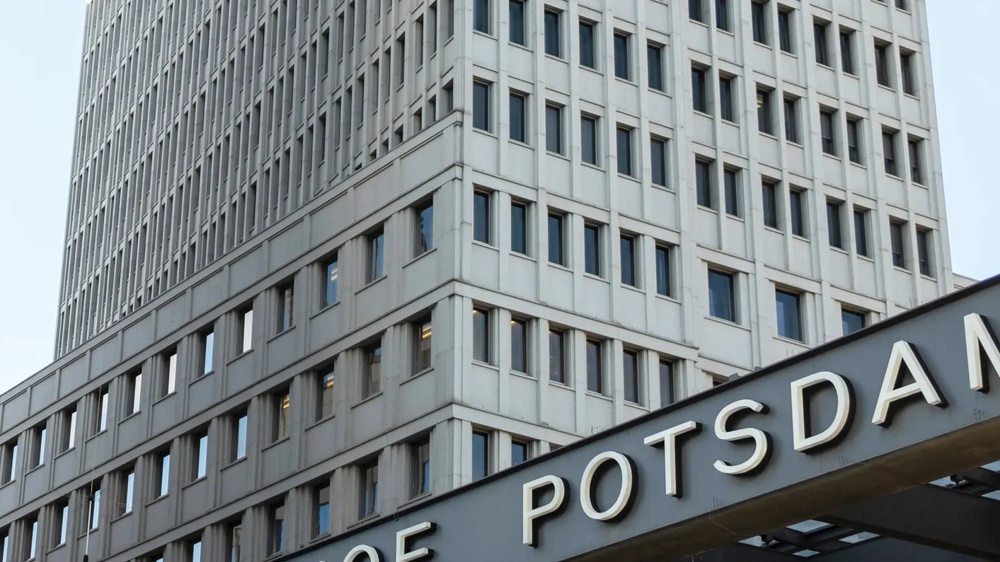 Ein graues Hochhaus mit vielen Fenstern, darüber ein Schild mit der Aufschrift "Bahnhof Potsdamer Platz".