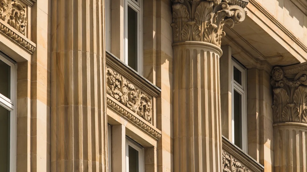 Decorated stone column with Corinthian chapter and floral reliefs on a classic building.