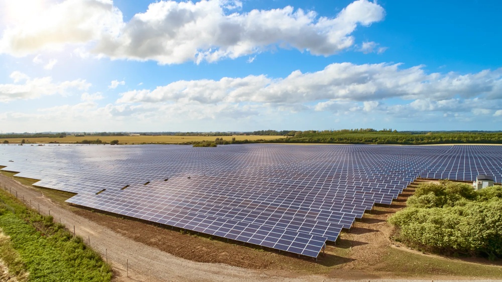 Ein großes Feld mit Solarpaneelen unter einem blauen Himmel mit weißen Wolken.
