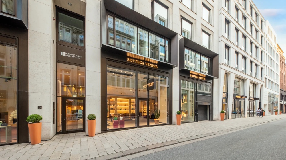 Fassade eines modernen Gebäudes mit Bottega Veneta Geschäft, großen Fenstern und Pflanzkübeln auf dem Gehweg.