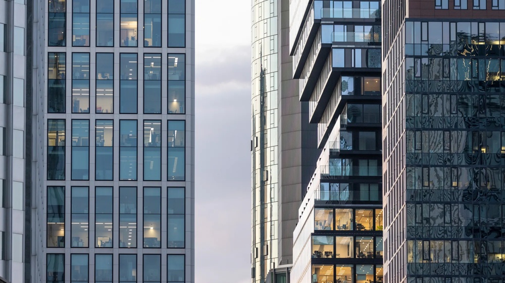 Moderne Hochhäuser mit Glasfassaden bei Tageslicht, dicht nebeneinander stehend.