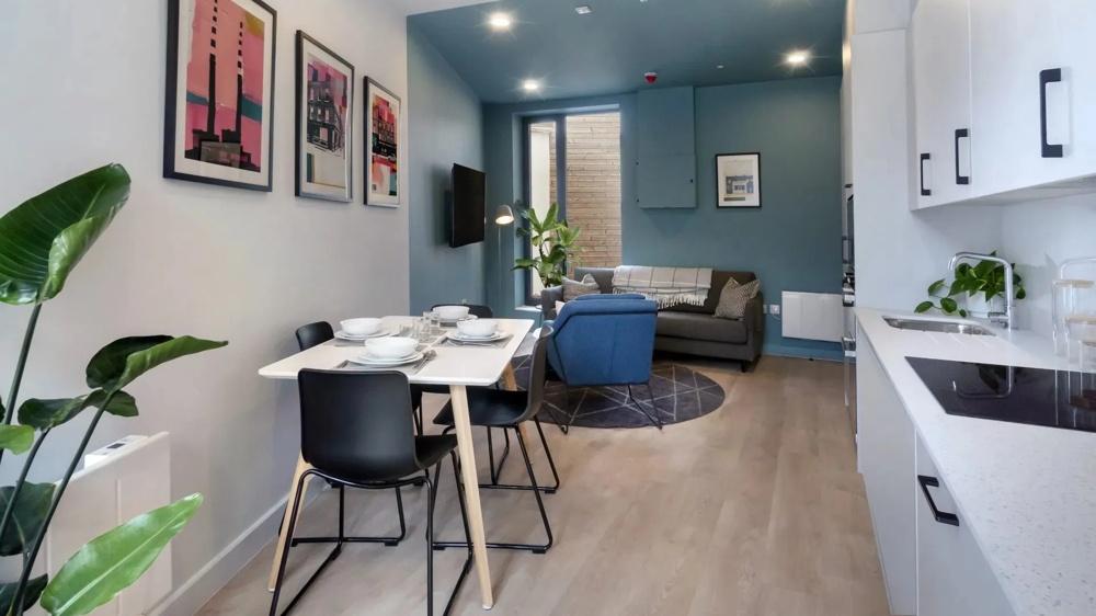 Modernes Wohnstudio im Studentenwohnheim Stoneybutter, Dublin – offener Wohn- und Küchenbereich mit Esstisch, Couch und farbigen Kunstdrucken – ein Objekt des Institutional Smart Living Europe Fund der Commerz Real.