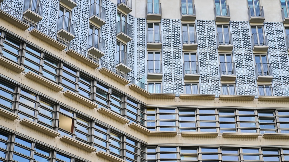 Fassade eines modernen Gebäudes mit vielen Fenstern und dekorativen Elementen in einem geometrischen Muster.