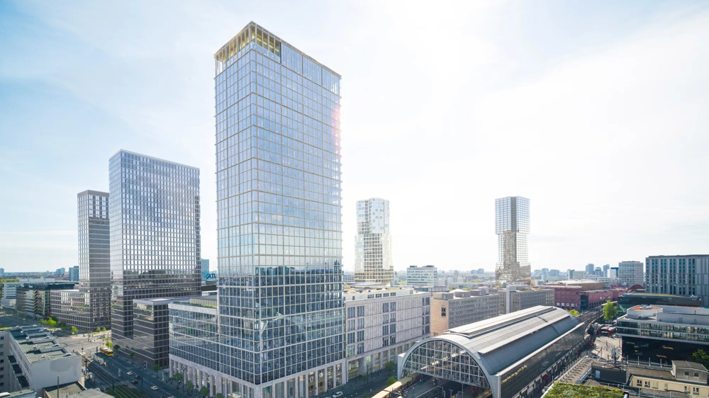 Modern city view with high-rise buildings, a large train station and a passing yellow subway under a clear sky.