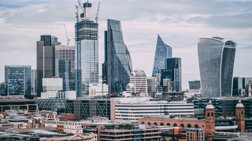 Moderne Londoner Skyline mit Wolkenkratzern und Baukränen unter bewölktem Himmel.