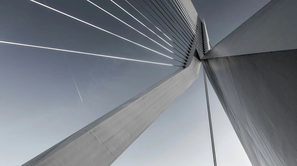 Modern wedge rope bridge with clear lines against a blue sky, diagonal perspective.