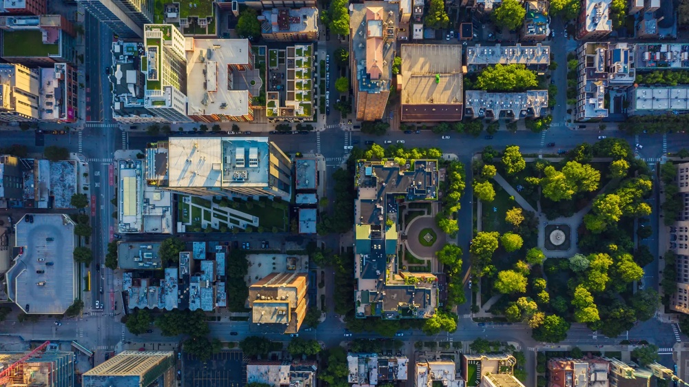 Draufsicht auf eine Stadt mit Gebäuden, Straßen und einem grünen Park mit Bäumen in der Mitte.