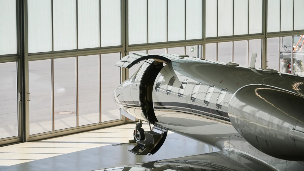 Ein Privatjet steht in einem Hangar, mit geöffneter Tür und heruntergelassener Treppe.