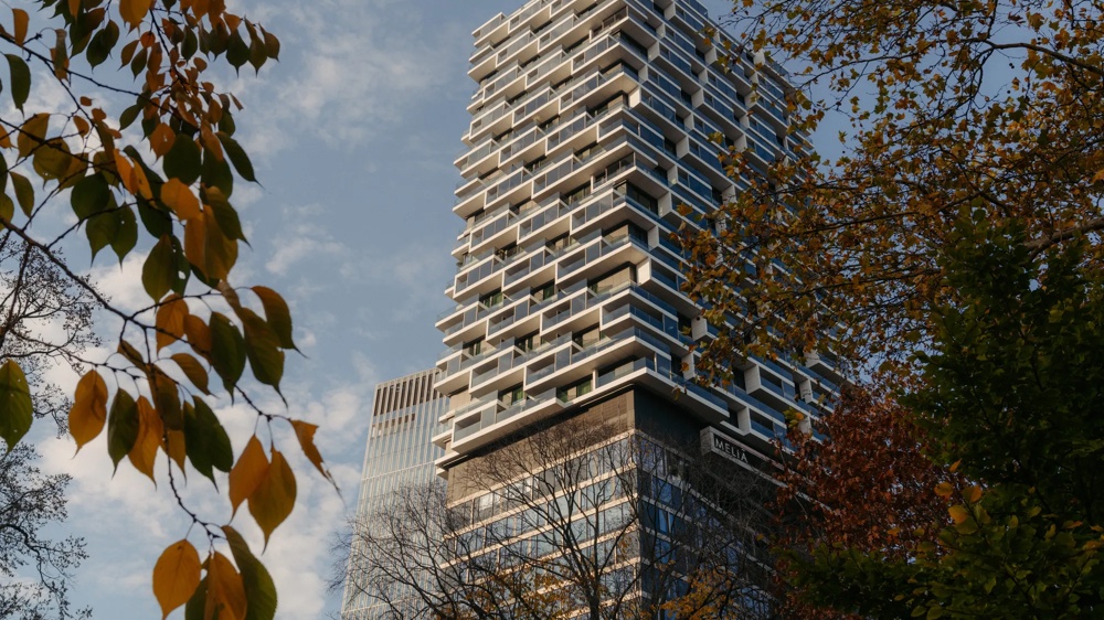 Hochhaus mit markanter Fassade, umgeben von Bäumen.