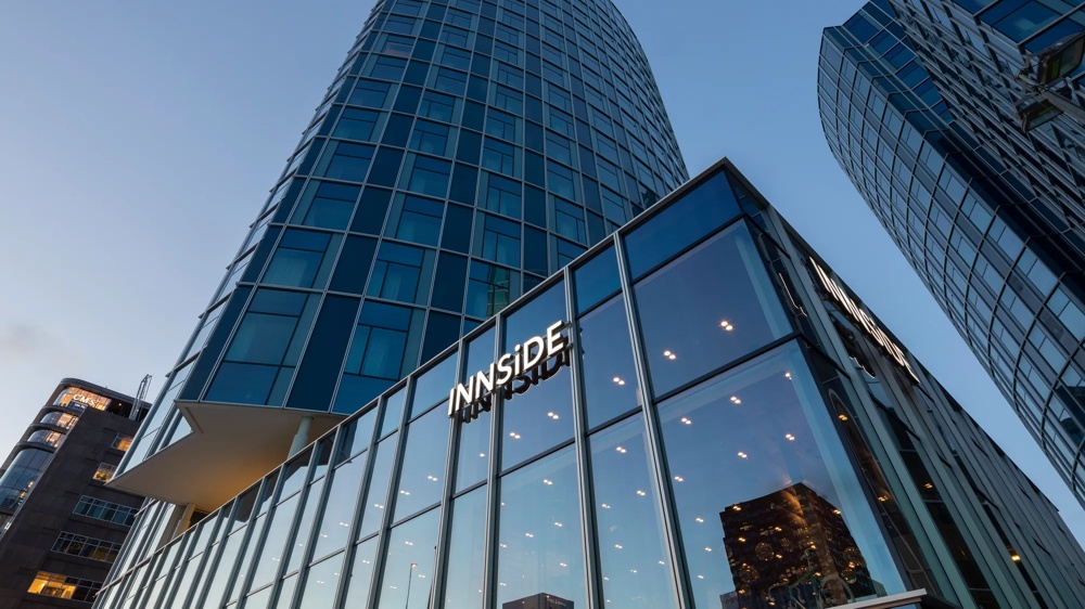 Modern high-rise building with glass facade and “INNSiDE” lettering at dusk.