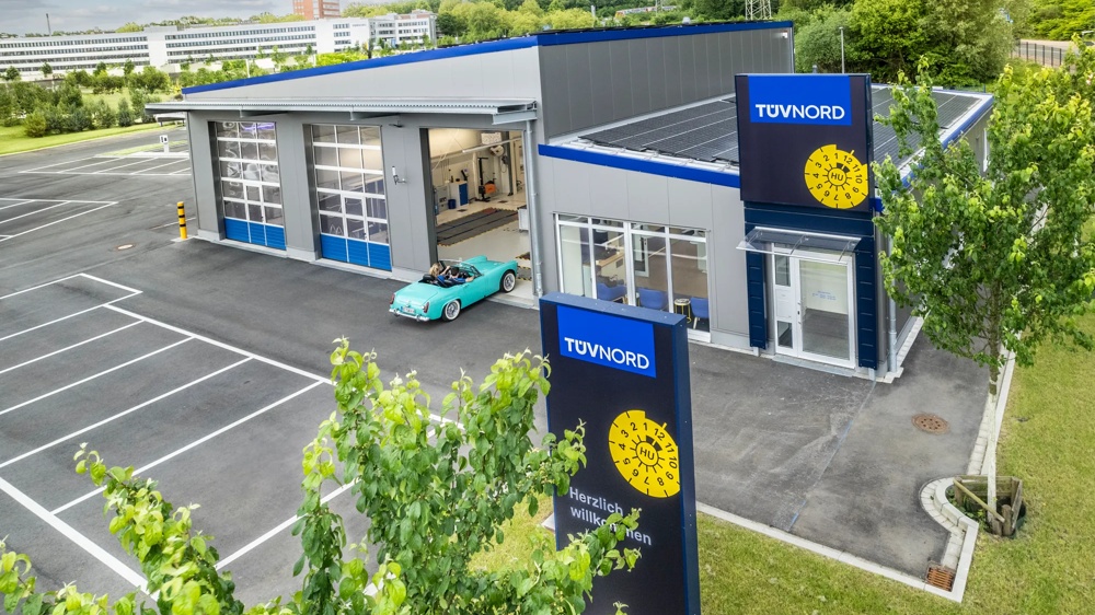 Parkplatz mit einer Autowerkstatt von oben, die vom TÜV Nord betrieben wird