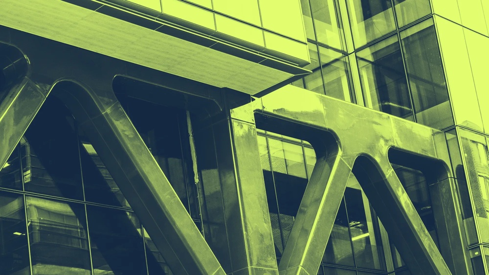 Moderne Glasfassade mit großen, diagonal verlaufenden Metallträgern.