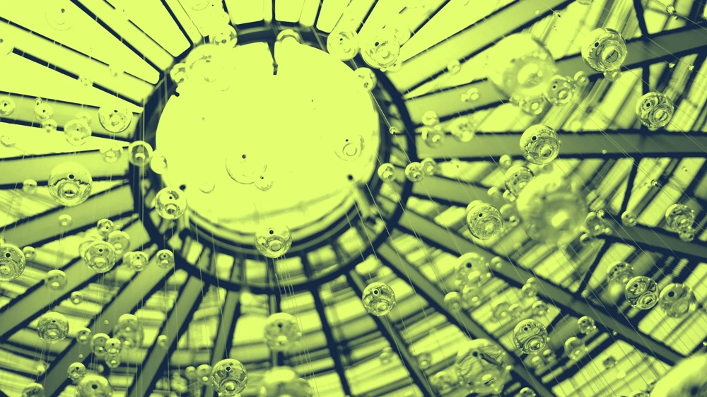 Blick durch ein gläsernes Dach mit hängenden Glasblasen, die in hellem Licht schimmern.