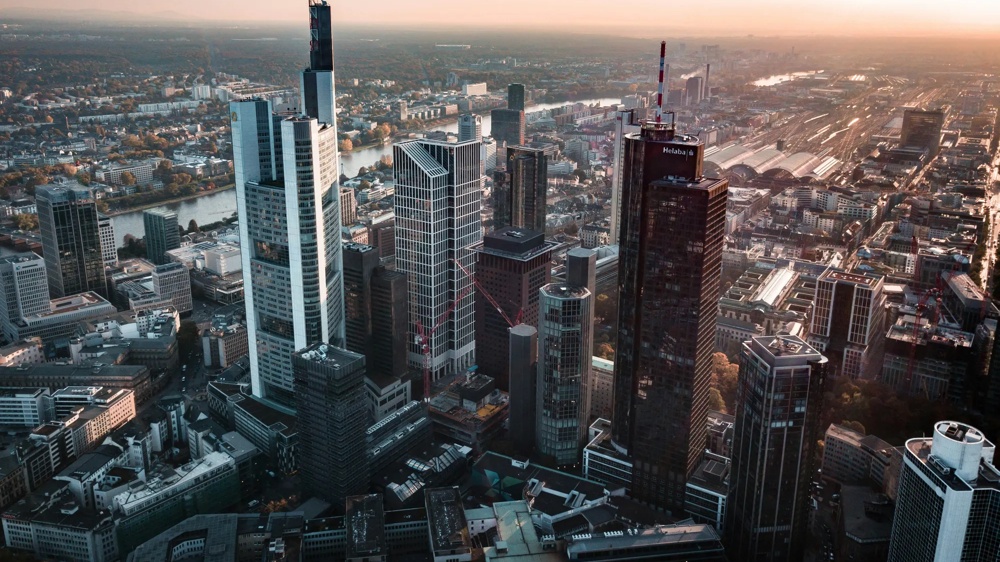 Aerial shot of Frankfurt’s skyline at sunset, with high skyscrapers and the Main in the background.
