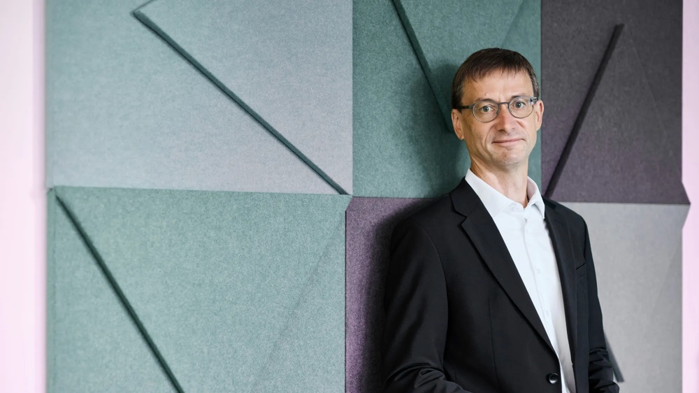 Markus Eismann is Chairman of the Management Board of Commerz Real Mobilienleasing. Markus Eismann leans against a blue wall sculpture.