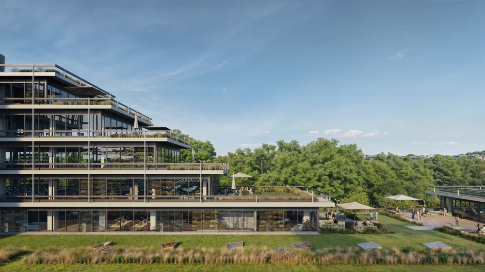 Modernes Gebäude mit Glasfassade und Terrassen, umgeben von grünen Bäumen unter blauem Himmel.