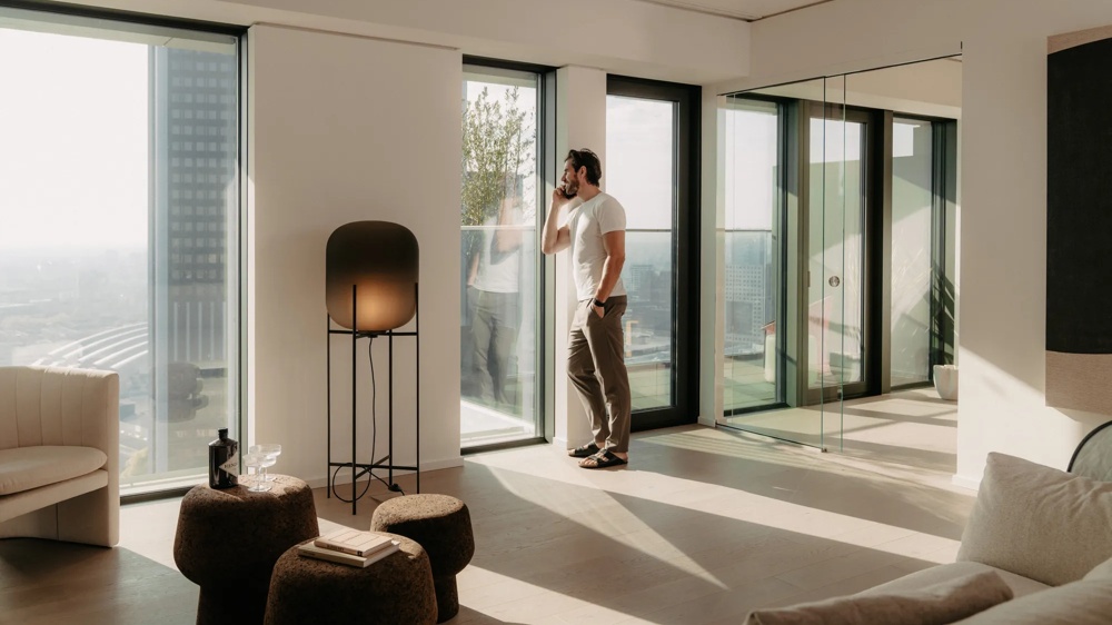 Person im Wohnzimmer einer modernen Wohnung mit bodentiefen Fenstern.