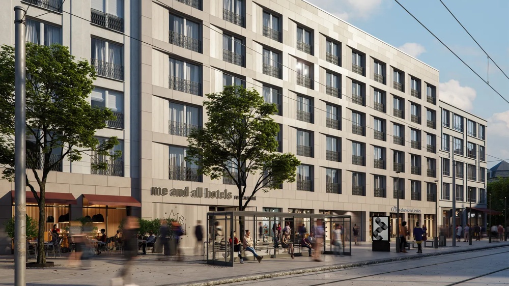 Visualisierung der Straßenfassade des Krystallpalast-Areals Leipzig mit „me and all hotels"-Eingang im Erdgeschoss, belebtem Gehweg und Straßenbahnlinie – ein hausInvest-Objekt.