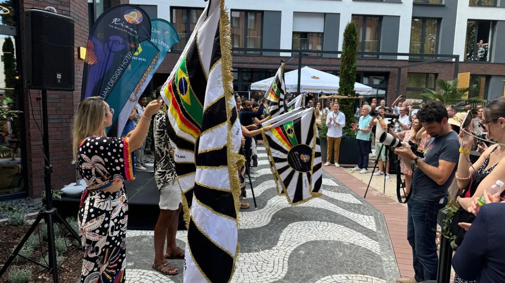People swinging Brazilian flags at an outdoor event while a photographer is taking pictures.