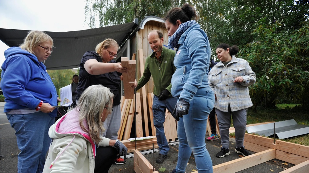 Eine Gruppe von Menschen baut gemeinsam ein Holzprojekt im Freien.