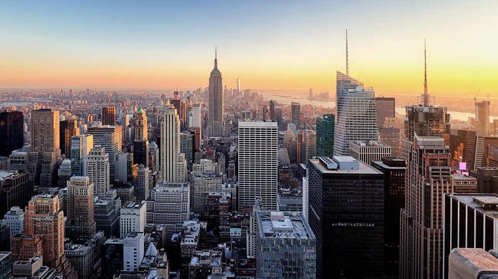 Stadtpanorama mit Hochhäusern bei Sonnenuntergang, Himmel in Orange und Blau.