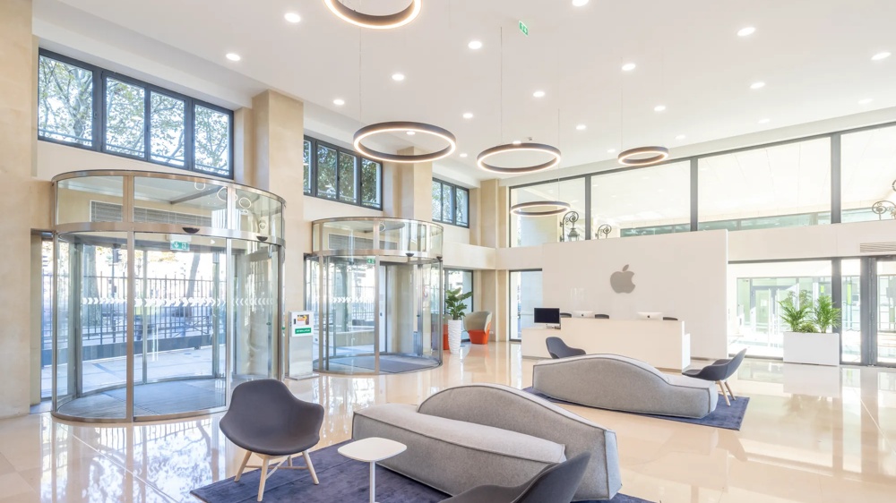 Heller Empfangsbereich mit modernen Möbeln, runden Lichtern und Glasdrehtüren.