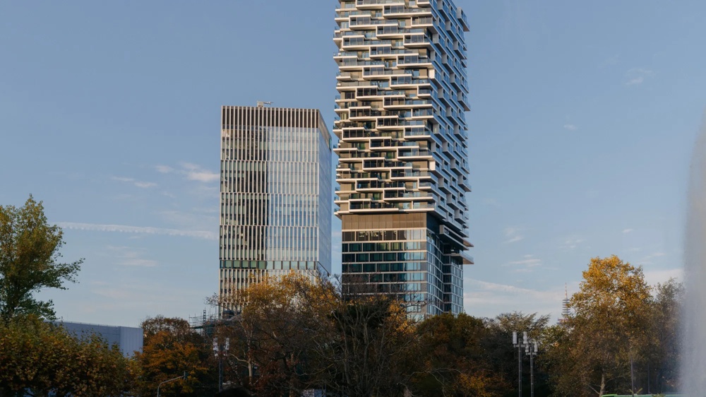 Hochhaus mit markanter Fassade, umgeben von Bäumen.