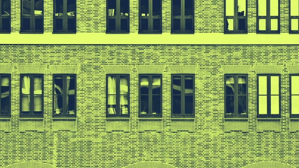 Backsteinfassade mit drei Bögen und neun Fenstern in Gelbtönen.