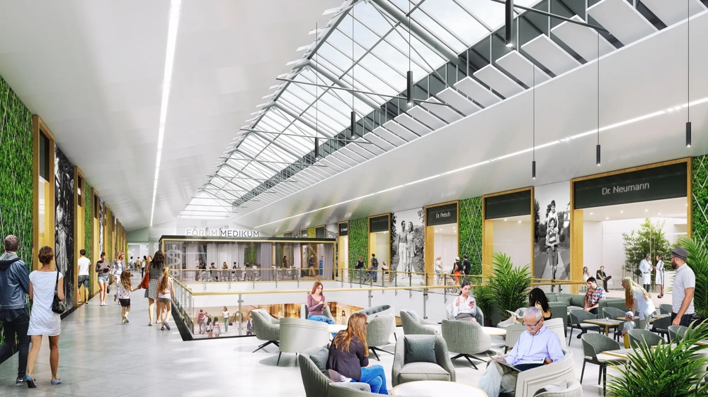 People walk through a modern shopping centre with a glass roof and green walls.
