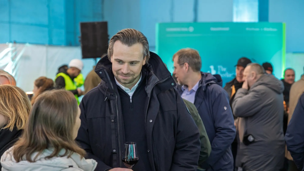 Personen stehen in einer Menschenmenge und unterhalten sich. Der Hintergrund ist belebt.