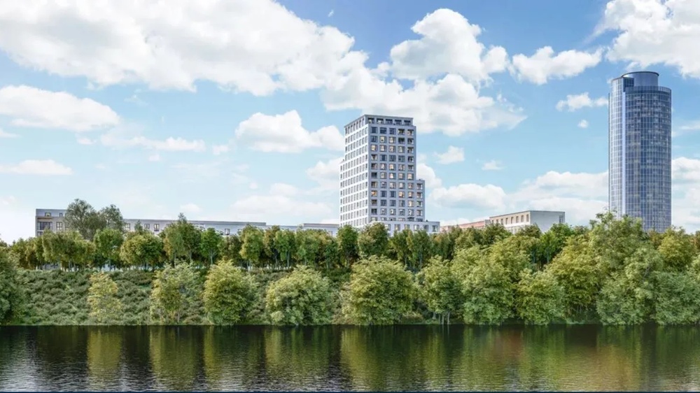 Zwei moderne Hochhäuser hinter einer Baumreihe spiegeln sich in einem Fluss, unter blauem Himmel mit Wolken.
