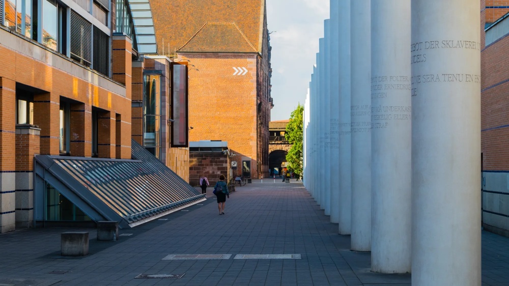Ein Weg zwischen modernen Gebäuden und weißen Säulen, mit Menschen, die in der Ferne gehen.