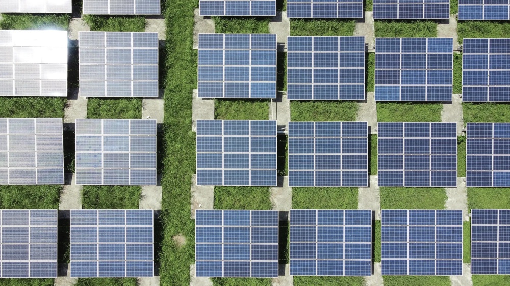 Luftaufnahme von Solarzellenfeldern auf grünem Gras.