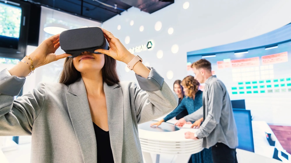 We see a woman in the foreground looking through VR glasses.