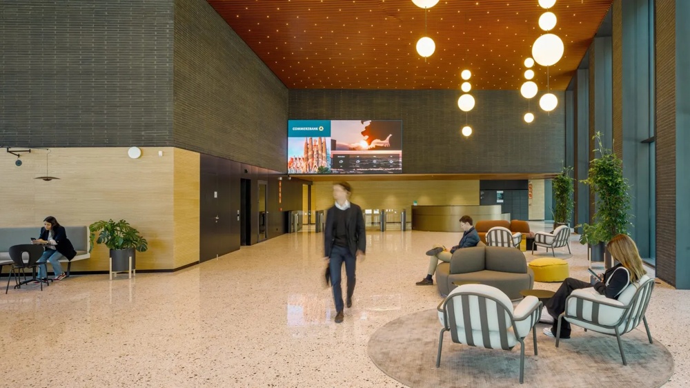 Sitzbereich in einer Lobby mit mehreren Personen und Lounge-Möbeln.