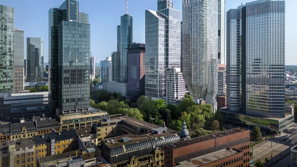 Skyline of modern high-rise buildings overlooking rooftops and green areas.