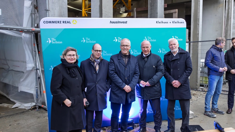 Gruppe von Projektbeteiligten steht für ein Foto vor der gebrandeten Pressewand.