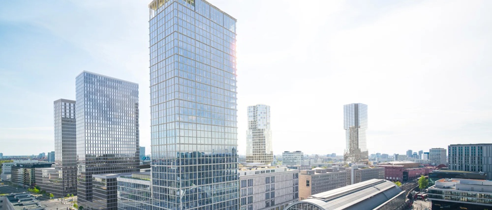 Moderne Stadtansicht mit Hochhäusern, einem großen Bahnhof und einer vorbeifahrenden gelben S-Bahn unter klarem Himmel.