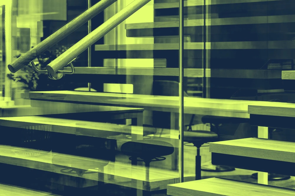 Eine moderne Treppe mit Glasgeländer und Holzstufen in einem Bürogebäude.