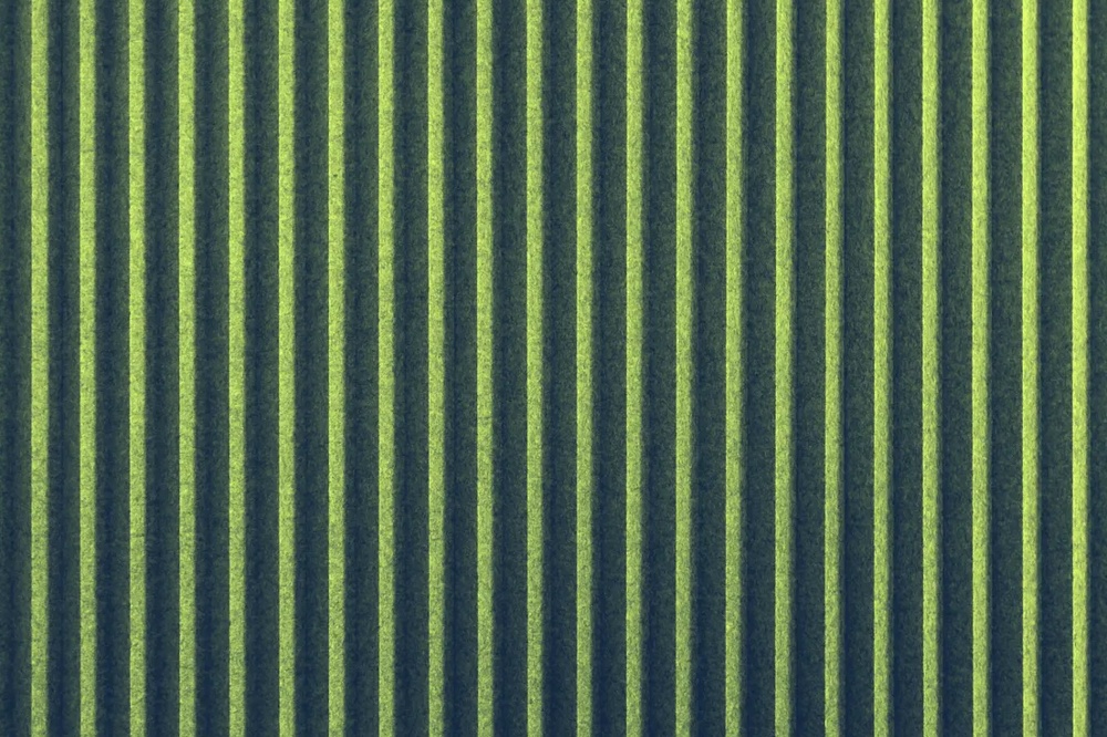 Zwei hängende Lampen vor einer gerippten Wand, darunter eine schwarze Bank auf hellem Boden.