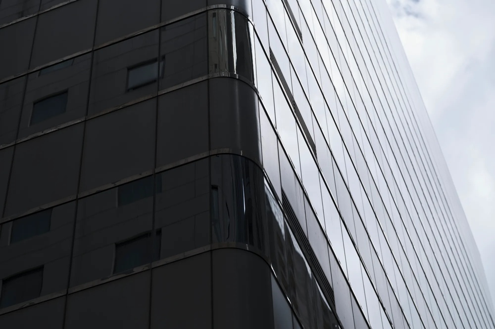 Ein modernes Hochhaus mit verspiegelter Glasfassade unter bewölktem Himmel.