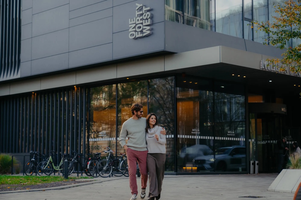 Zwei Personen gehen im Außenbereich vor einem Gebäude.
